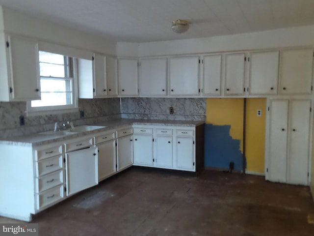 kitchen featuring light countertops, tasteful backsplash, a sink, and white cabinets