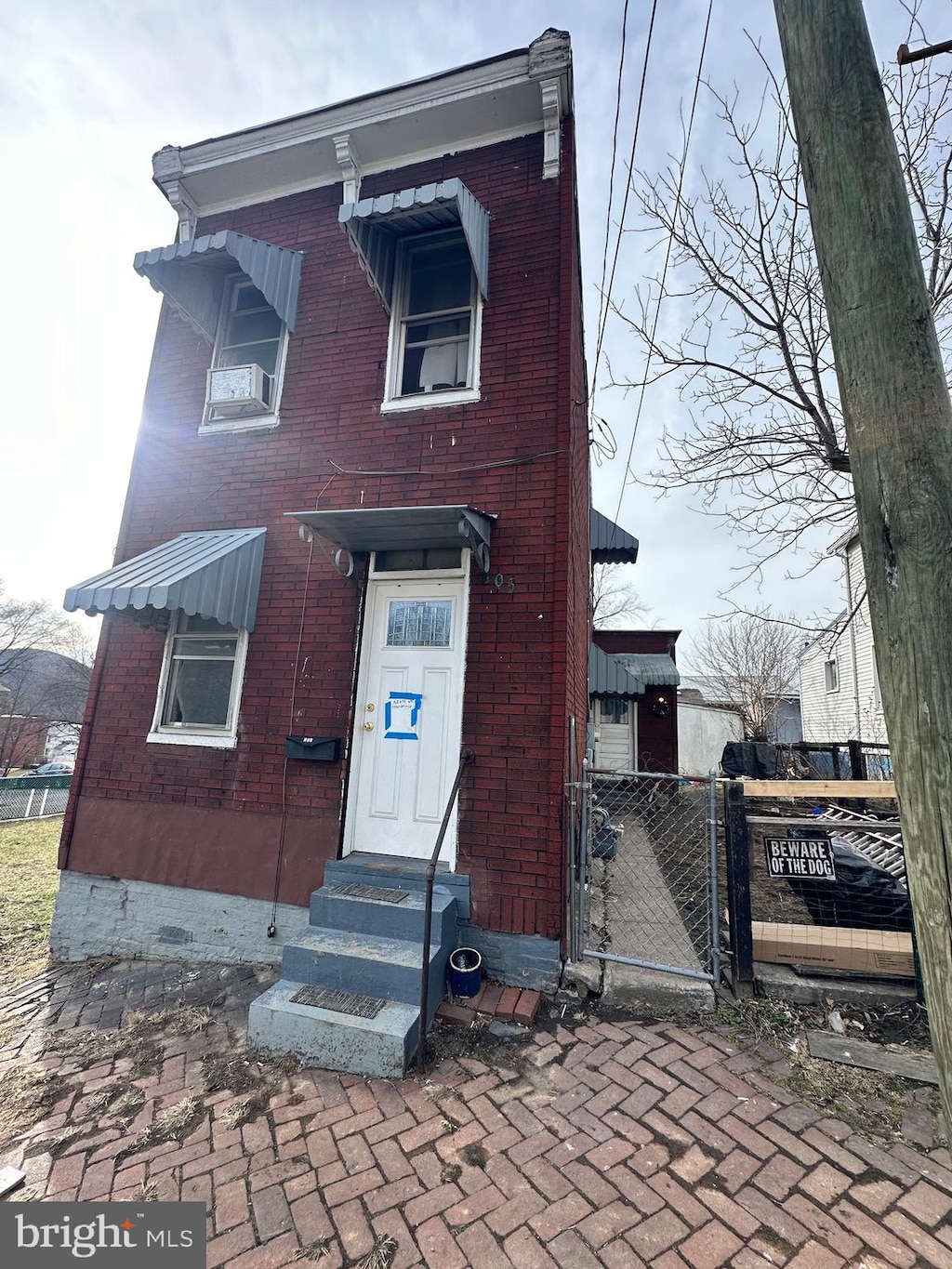 view of front of property featuring entry steps, brick siding, fence, and a gate