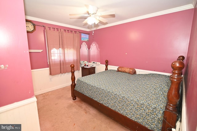 carpeted bedroom featuring a wainscoted wall, a ceiling fan, and crown molding