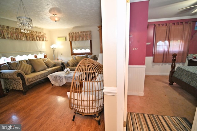 living area with a wainscoted wall, crown molding, a textured ceiling, and wood finished floors