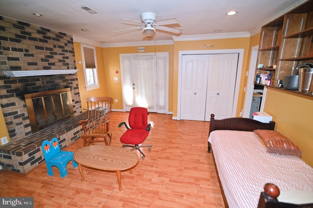 bedroom with ornamental molding, a fireplace, wood finished floors, and visible vents