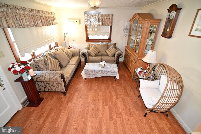 living area featuring light wood-style floors, a textured ceiling, baseboards, and crown molding