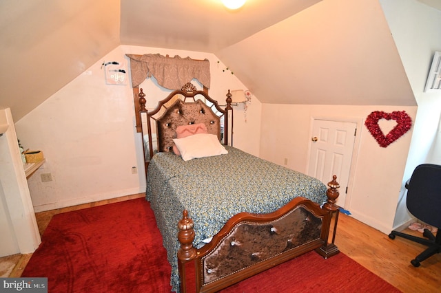 bedroom featuring lofted ceiling, baseboards, and wood finished floors