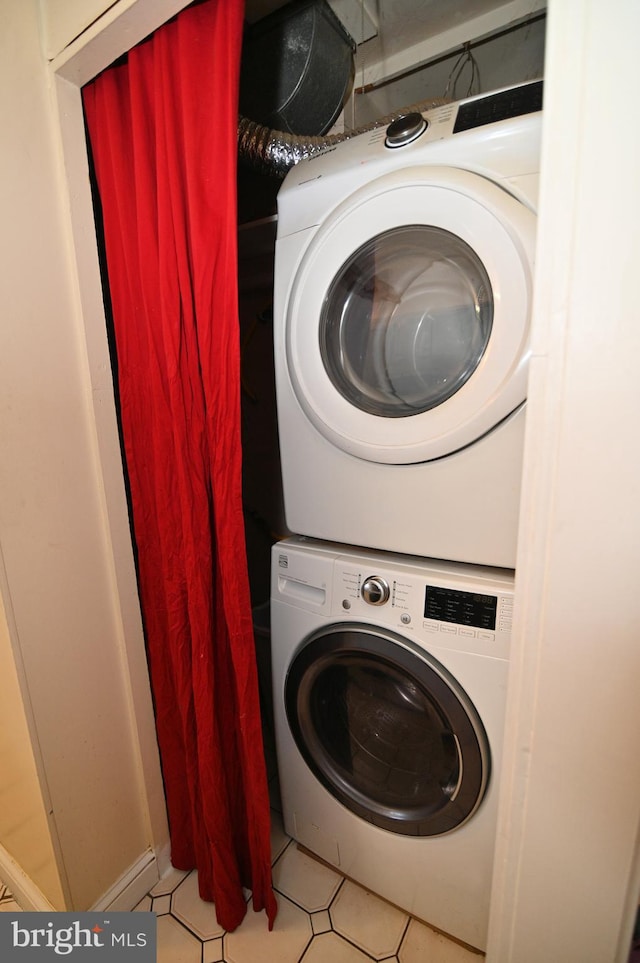 laundry area with stacked washing maching and dryer, tile patterned flooring, and laundry area