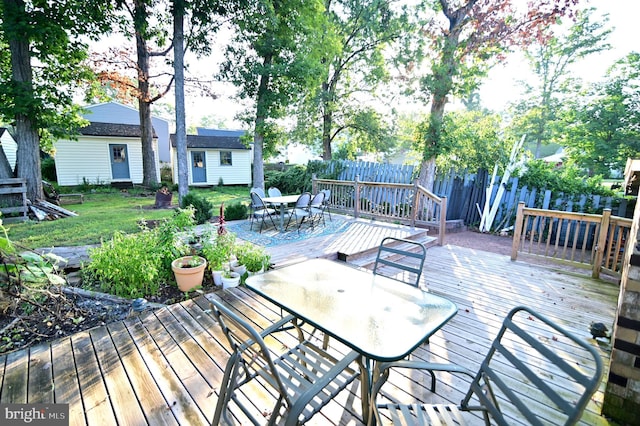 deck with a yard, outdoor dining area, and fence