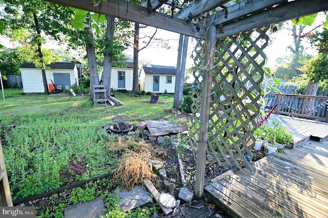 view of yard with an outdoor fire pit, an outbuilding, a wooden deck, and a storage unit