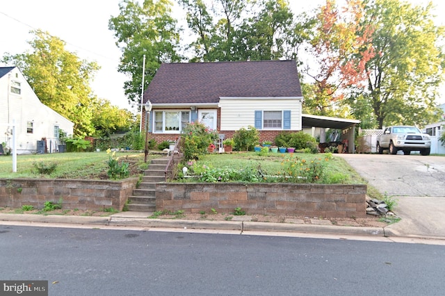 view of front of property featuring roof with shingles, an attached carport, concrete driveway, and brick siding