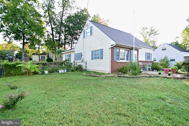 view of side of home with a patio area, brick siding, and a yard