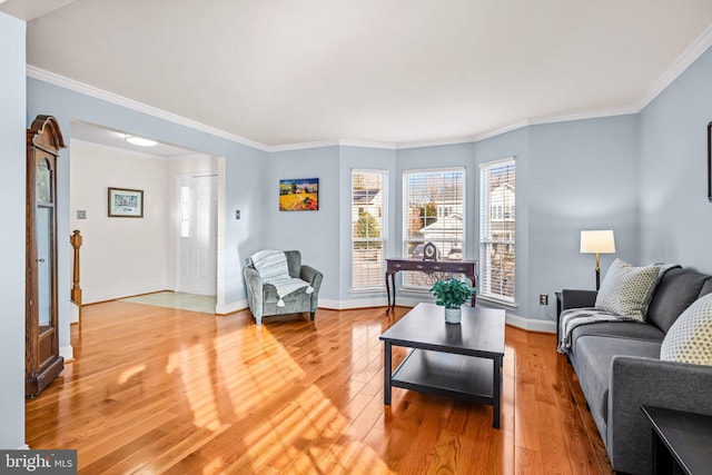 living area featuring light wood-style floors, crown molding, and baseboards