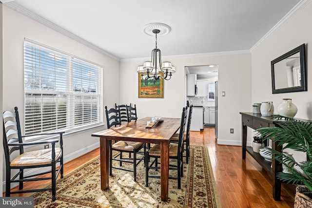 dining space featuring ornamental molding, baseboards, an inviting chandelier, and wood finished floors