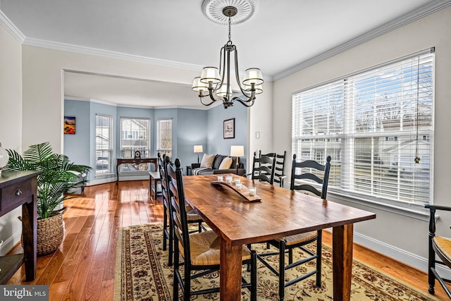 dining space with a chandelier, baseboards, hardwood / wood-style flooring, and crown molding