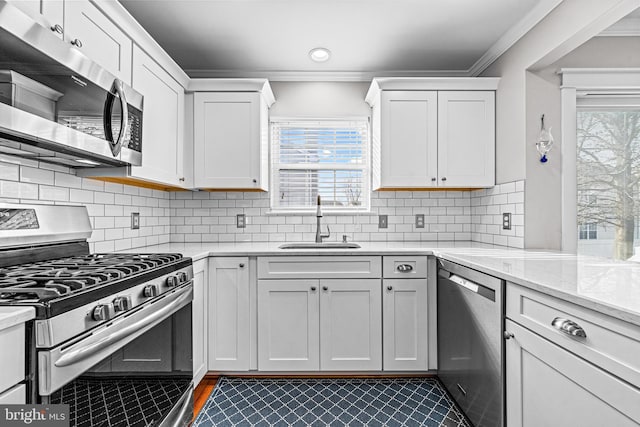 kitchen featuring stainless steel appliances, plenty of natural light, crown molding, and a sink