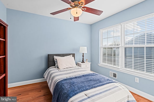 bedroom featuring visible vents, ceiling fan, baseboards, and wood finished floors