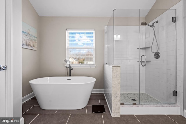 full bath featuring tile patterned flooring, a freestanding tub, a shower stall, and baseboards