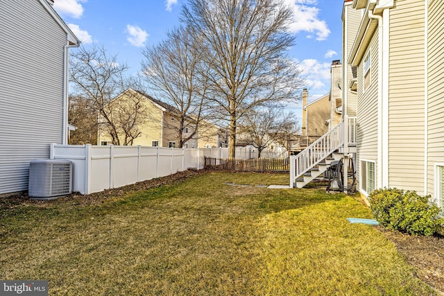 view of yard with stairway, fence, and central air condition unit