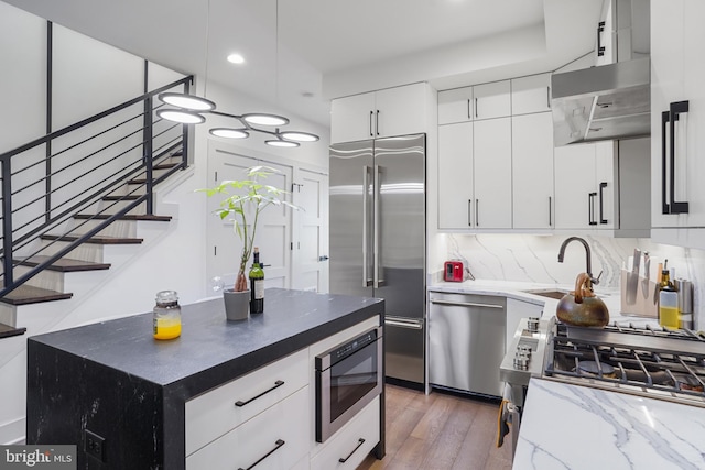 kitchen featuring decorative light fixtures, stainless steel appliances, tasteful backsplash, a sink, and under cabinet range hood