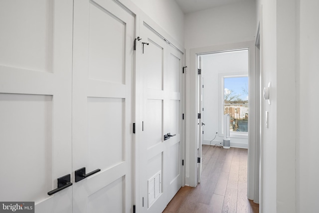 hallway featuring visible vents and wood finished floors