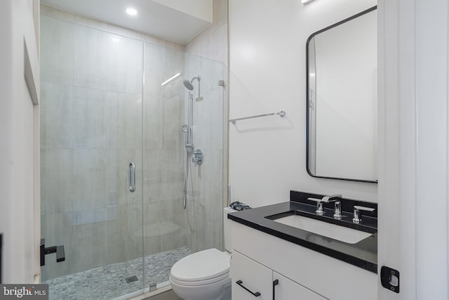 bathroom with vanity, a shower stall, and toilet