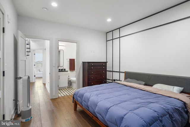 bedroom with hardwood / wood-style floors, connected bathroom, and recessed lighting