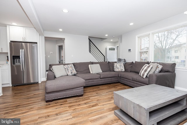 living area featuring stairs, light wood-type flooring, baseboards, and recessed lighting