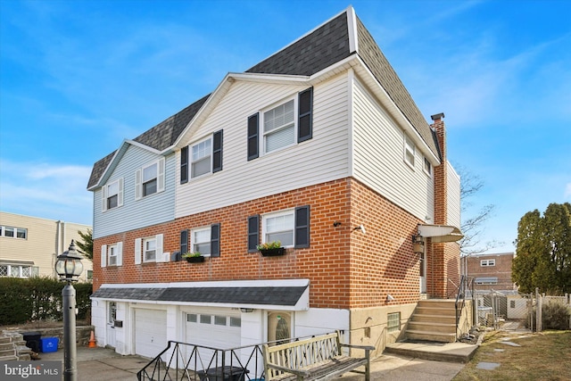 2766 Clayton St, Philadelphia, PA 19152 - view of front facade featuring a garage, brick siding, concrete driveway, roof with shingles, and a chimney