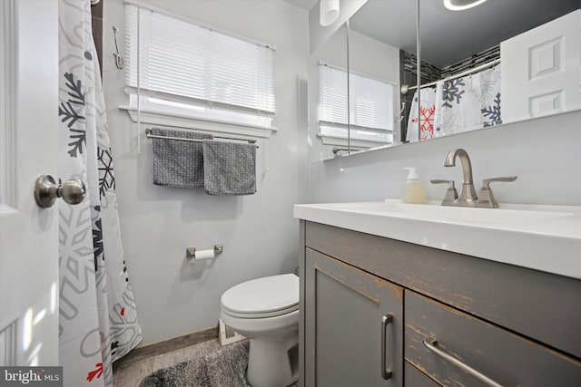 bathroom with toilet, wood finished floors, a wealth of natural light, and vanity