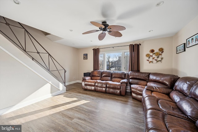 living area with stairs, ceiling fan, wood finished floors, and baseboards