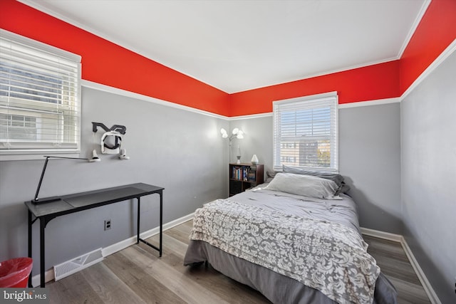 bedroom featuring wood finished floors, visible vents, and baseboards