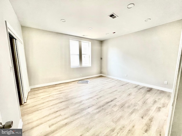 empty room featuring wood finished floors, visible vents, and baseboards