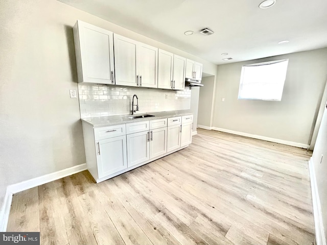 kitchen featuring tasteful backsplash, light countertops, a sink, and light wood-style flooring