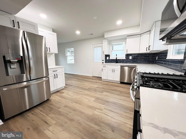 kitchen featuring white cabinetry, light wood finished floors, tasteful backsplash, and appliances with stainless steel finishes