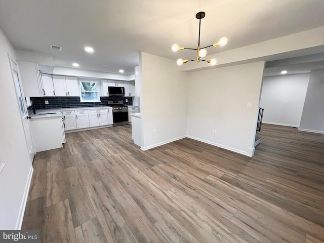 kitchen featuring stainless steel appliances, wood finished floors, visible vents, white cabinetry, and tasteful backsplash