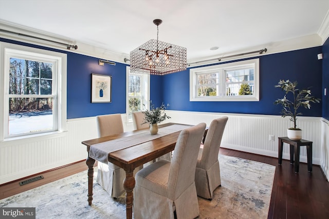 dining room featuring visible vents, wainscoting, hardwood / wood-style flooring, and crown molding