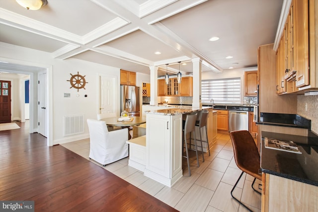 kitchen featuring a breakfast bar, a sink, visible vents, appliances with stainless steel finishes, and a center island