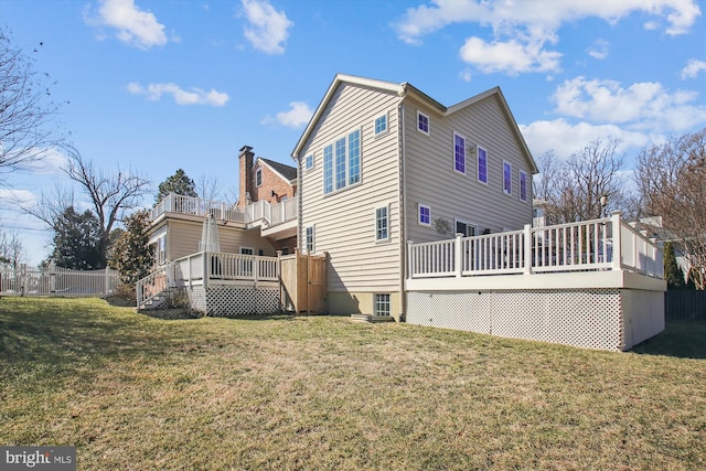 rear view of property with a yard, a wooden deck, and fence