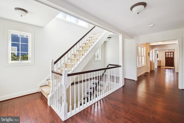 staircase featuring plenty of natural light, hardwood / wood-style flooring, and baseboards