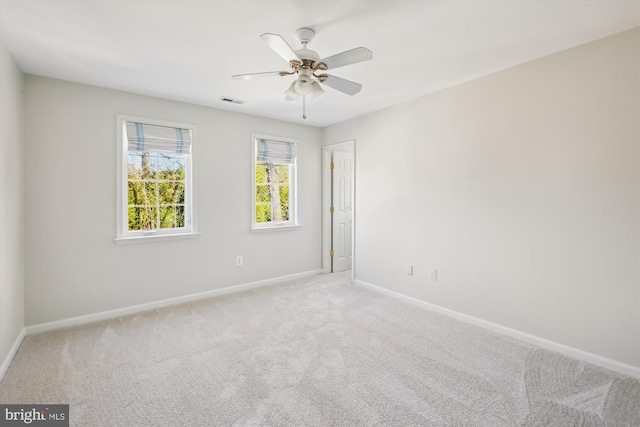 empty room featuring a ceiling fan, carpet flooring, visible vents, and baseboards