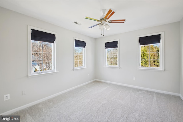 carpeted empty room with a ceiling fan, visible vents, and baseboards