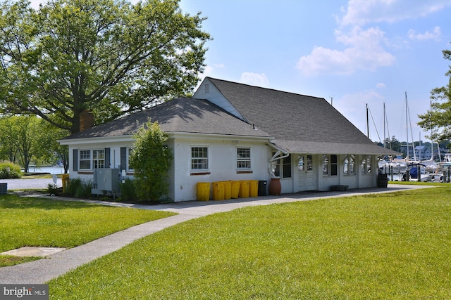 view of front of house featuring a front lawn, roof with shingles, and central AC unit