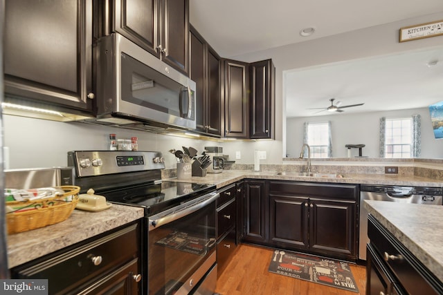 kitchen featuring dark brown cabinetry, light wood-style flooring, appliances with stainless steel finishes, and a sink