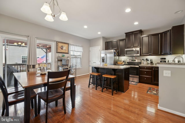 dining room featuring light wood finished floors, recessed lighting, and baseboards