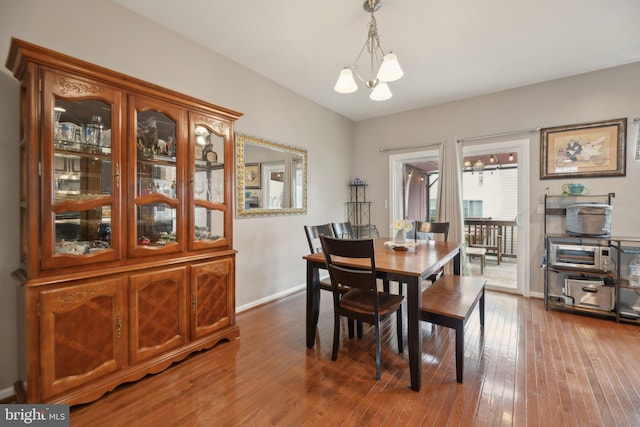 dining space featuring baseboards, vaulted ceiling, an inviting chandelier, and hardwood / wood-style flooring