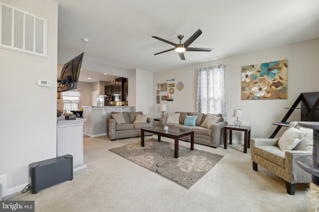 living area featuring visible vents, ceiling fan, light carpet, and baseboards