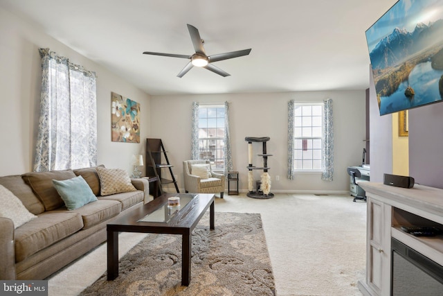 living area with light colored carpet, ceiling fan, and baseboards