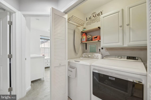 clothes washing area with separate washer and dryer and cabinet space