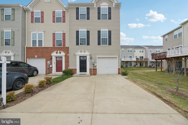 view of property featuring a front yard, concrete driveway, brick siding, and an attached garage