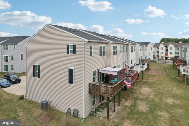 back of house with central air condition unit, a residential view, a deck, and a lawn