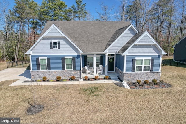 craftsman house with stone siding, a porch, and a front yard