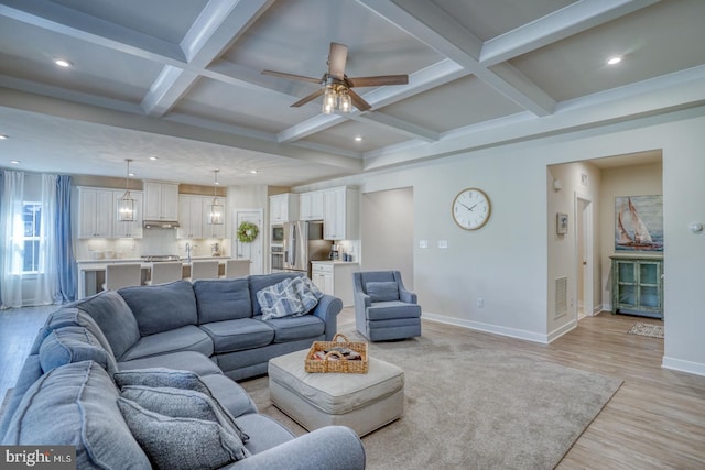 living room with beam ceiling, coffered ceiling, light wood-style flooring, and baseboards