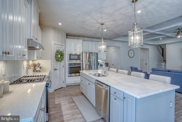 kitchen with stainless steel appliances, white cabinets, a sink, coffered ceiling, and under cabinet range hood